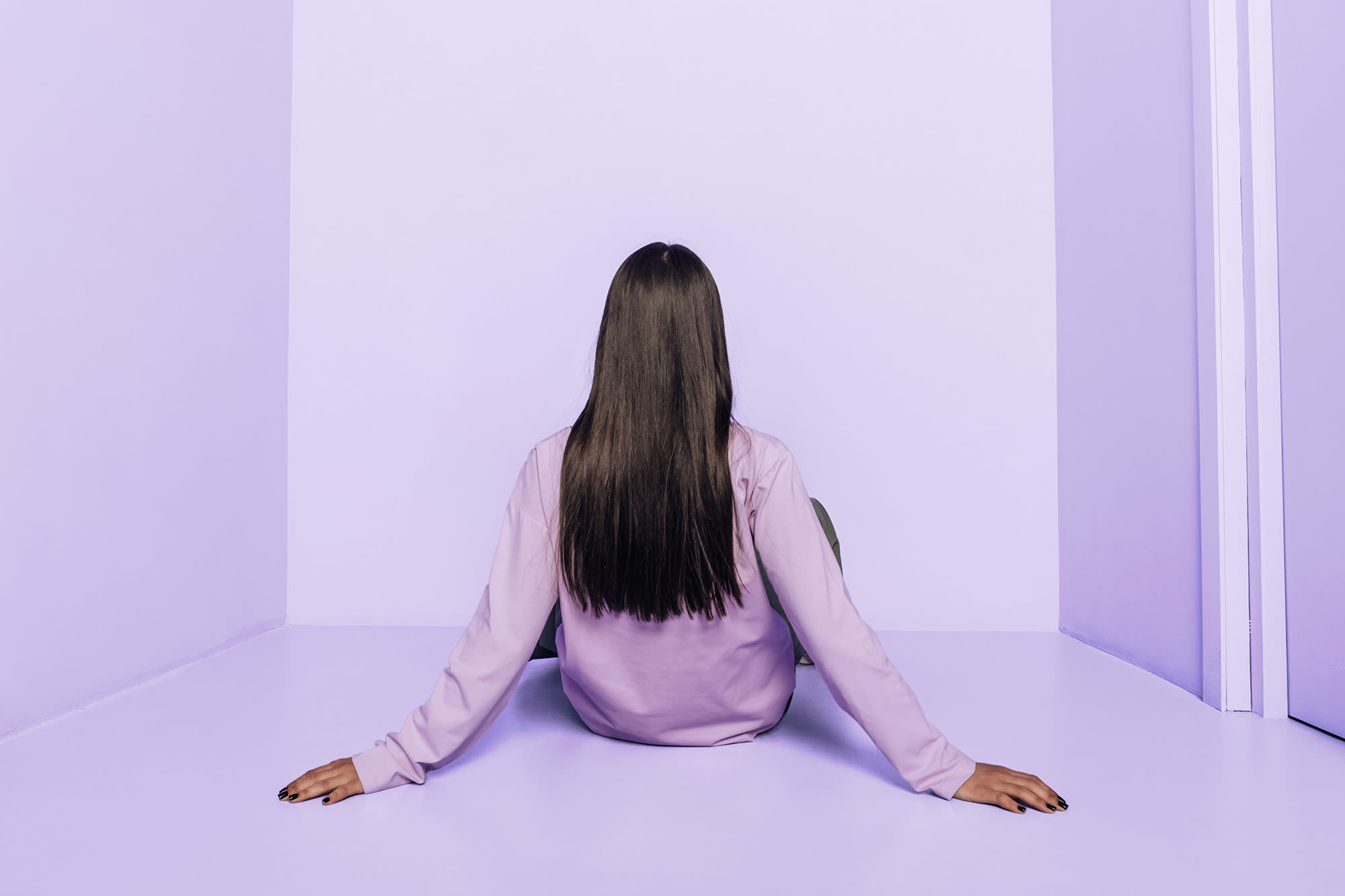 Žena sjedi u ljubičastoj prostoriji s leđima okrenutim kameri. Žena sjedi u ljubičastoj prostoriji s leđima okrenutim kameri.