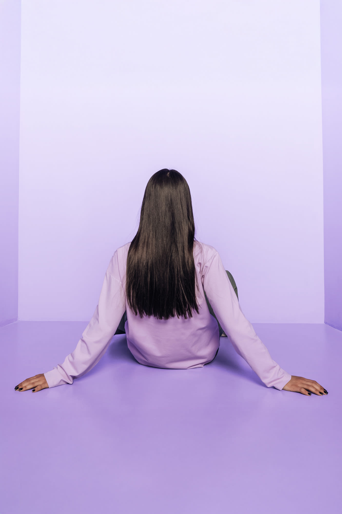 Žena sjedi u ljubičastoj prostoriji leđima okrenuta prema kameri. Žena sjedi u ljubičastoj prostoriji leđima okrenuta prema kameri.
